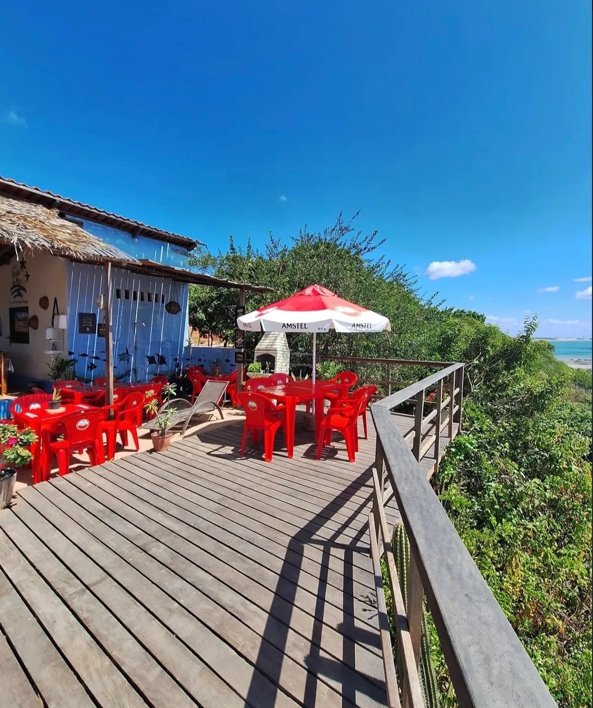 Deck da Brisa do Mar com mesas vermelhas e vista para o mar
